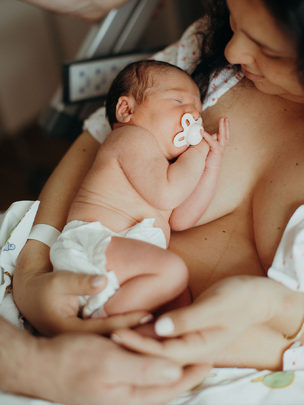 Fødselsfotografering baby med smokk i mors armer